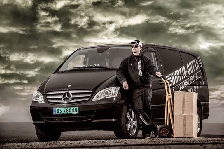 En ansatt fra transportfirmaet Hurtig Gutta Transport poserer ved en av firmaets biler
