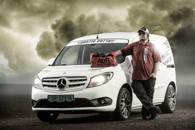 En ansatt ved Hurtig Gutta Transport som poserer med en av firmaets budbiler